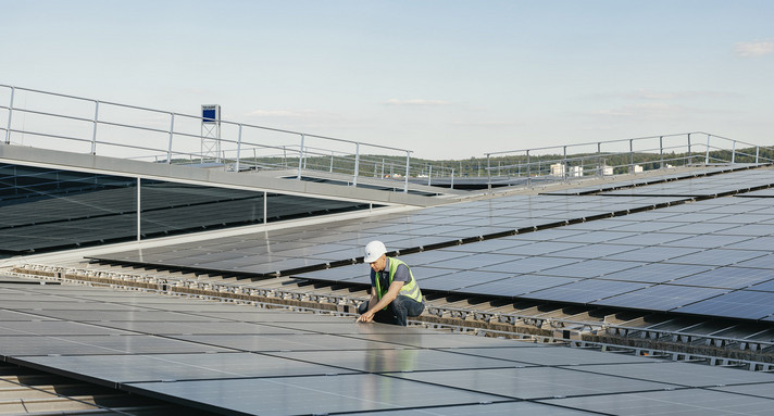 Ein Handwerker installiert eine Photovoltaik-Anlage.