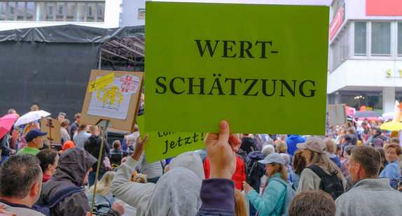 Menschenmenge mit Demonstrationsschildern, darunter mit der Aufschrift "Wertschätzung".