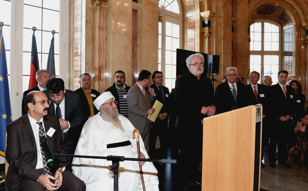 Staatssekretär Klaus-Peter Murawski (M.) bei seiner Ansprache und das religiöse Oberhaupt der Jesiden, Baba Sheikh (vordere Reihe 2.v.l.).