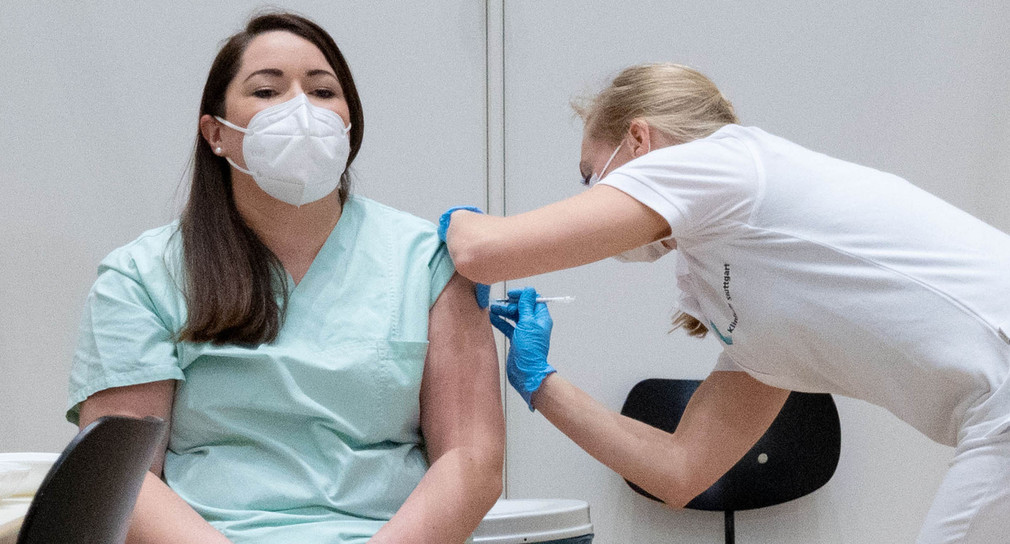 Eine Pflegekraft wird im Impfzentrum des Klinikums Stuttgart von einer Ärztin mit einer Dosis eines Covid-19-Impfstoffes geimpft.