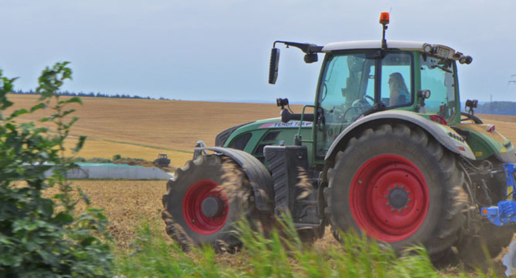 Eine Bäuerin fährt mit einem Traktor über ein Feld.