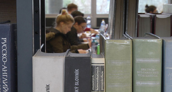 Studierende sitzen in einer Universitätsbibliothek und arbeiten.