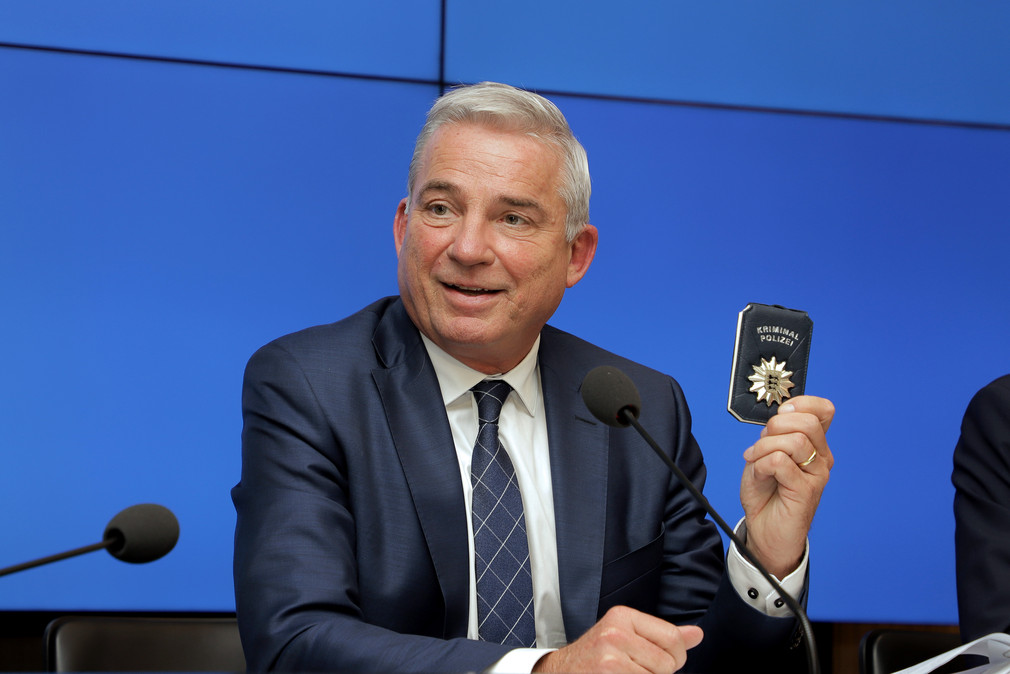 Innenminister Thomas Strobl hat bei der Regierungspressekonferenz eine Kriminalpolizei-Marke in der Hand. (Bild: Staatsministerium Baden-Württemberg)