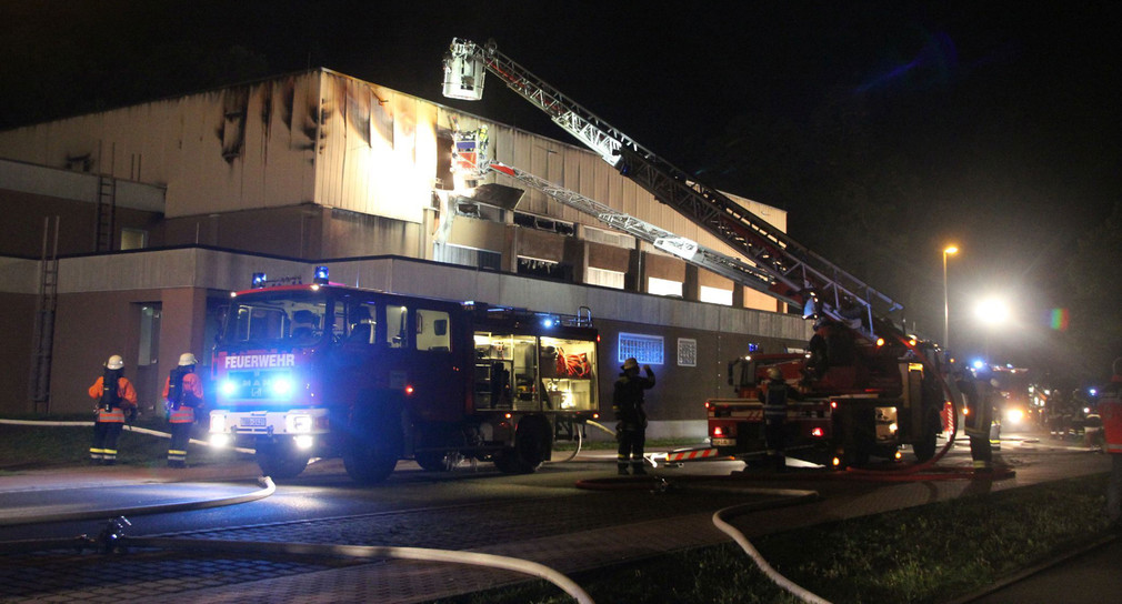 Einsatzkräfte der Feuerwehr löschen am 20.09.2015 in Wertheim einen Brand in einer geplanten Notunterkunft für Flüchtlinge (Foto: dpa)