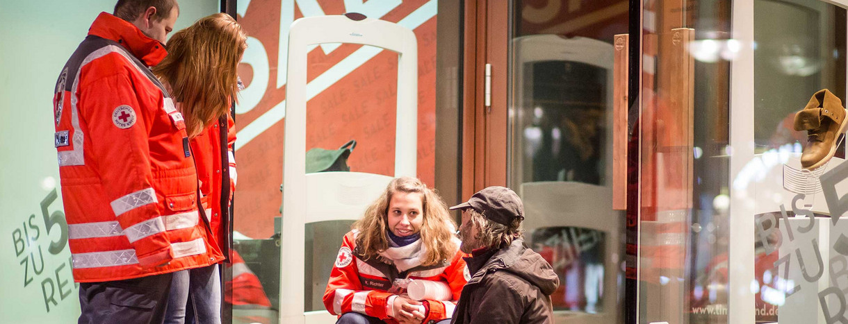 Ehrenamtliche Mitarbeiter vom Deutschen Roten Kreuz (DRK) und Teil des Teams vom Kältebus, versorgen am frühen Morgen auf der Königstrasse in Stuttgart einen Obdachlosen mit heißem Tee.