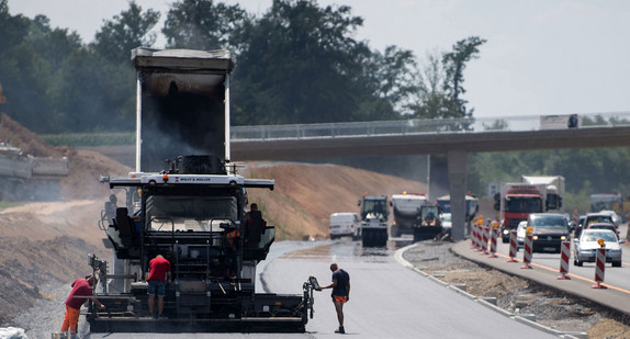 Eine Maschine teert den Straßenbelag der Baustelle des Neubaus der B14 Nellmersbach - Backnang/West. (Foto: © dpa)
