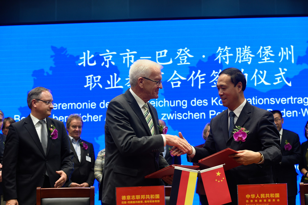 Ministerpräsident Winfried Kretschmann (M.) und ein Vertreter der Stadtregierung von Peking (r.) mit dem Memorandum of Understanding zur Zusammenarbeit in der beruflichen Bildung mit der Stadtregierung Peking