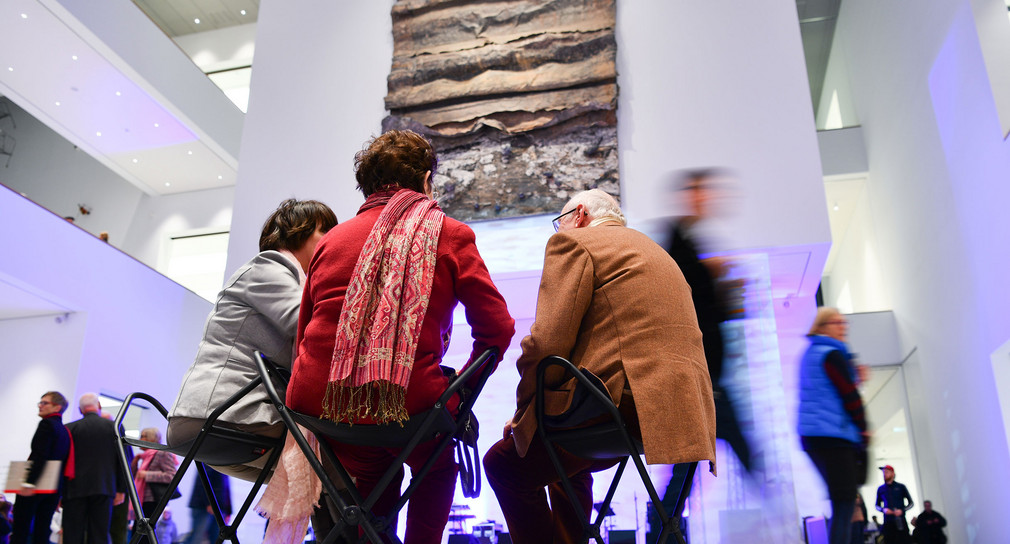 Besucher sitzen im Atrium der neu gebauten Kunsthalle Mannheim vor dem Kunstwerk „Sefiroth“ des Künstlers A. Kiefer (Bild: © dpa). 