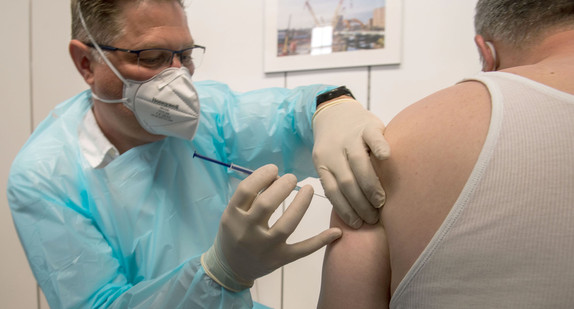 Ein Rettungsassistent impft im Impfzentrum des Maschinenbauers Liebherr einen Mann gegen Covid-19. 