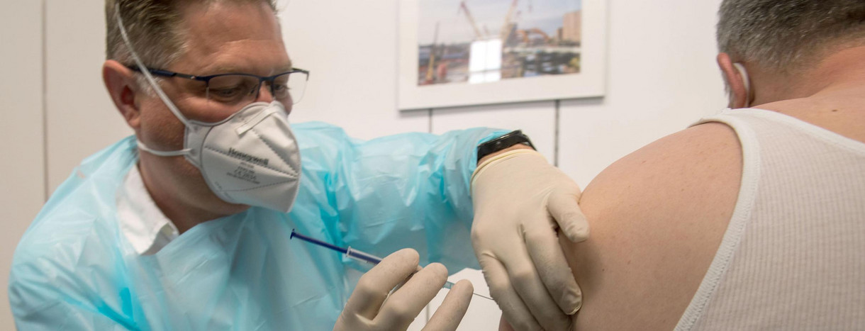 Ein Rettungsassistent impft im Impfzentrum des Maschinenbauers Liebherr einen Mann gegen Covid-19. 