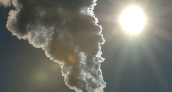 Rauch steigt aus einem Schornstein in einen wolkenlosen sonnigen Himmel auf. (Foto: © dpa)