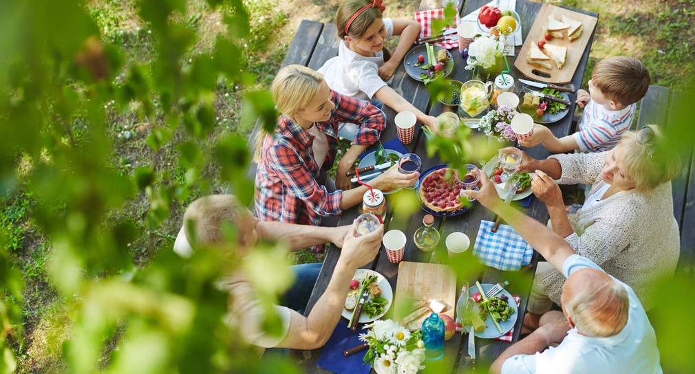 Menschen sitzen am Tisch im Garten und Essen gemeinsam