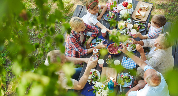 Menschen sitzen am Tisch im Garten und Essen gemeinsam