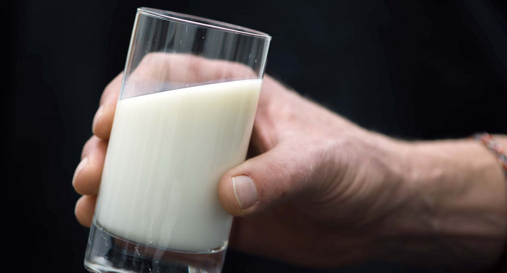Symbolbild: Ein Mann hält ein Glas Milch in der Hand. (Bild: Lukas Schulze / dpa)