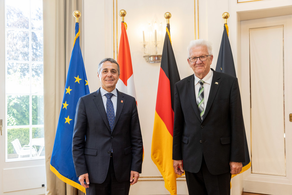 Ministerpräsident Winfried Kretschmann (rechts) und der Schweizer Bundespräsident Ignazio Cassis (links) stehen vor Fahnen.