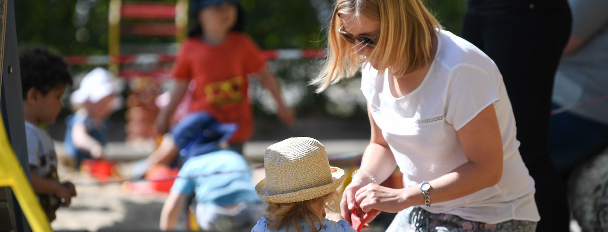 Eine Erzieherin spielt auf einem Spielplatz mit einem Kind.