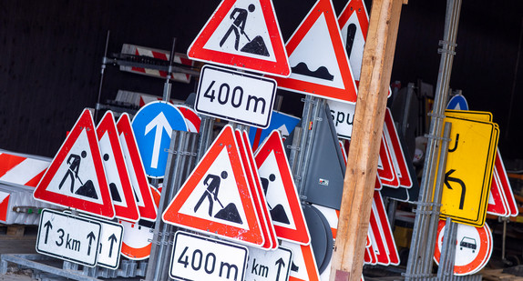 Mehrere Straßenschilder stehen in einem Schuppen nebeneinander.