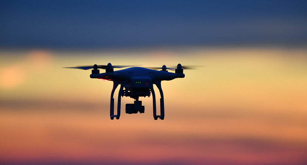 Eine Drohne fliegt bei Sonnenuntergang über eine Wiese. (Bild: picture alliance/Felix Kästle/dpa)