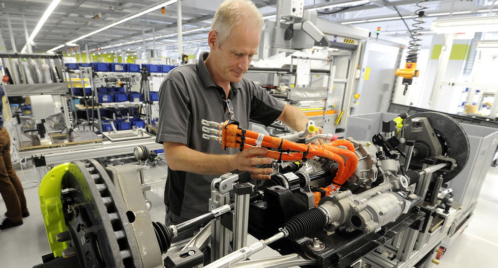 Ein Mitarbeiter montiert im Porsche Werk in Stuttgart-Zuffenhausen eine Vorderachse mit Elektromotor. (Foto: © dpa)
