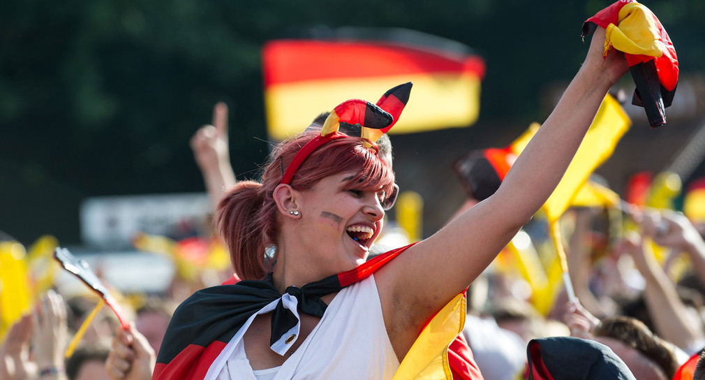 Fußballfans mit deutschen Fahnen auf einer Fanmeile währende eines Spiels der deutschen Fußballnationalmannschaft (Bild: © dpa).