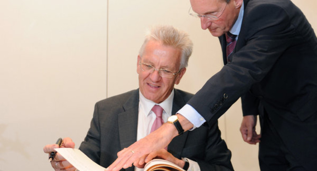 Ministerpräsident Winfried Kretschmann trägt sich am Dienstag (31.05.2011) bei einem Antrittsbesuch im Rathaus von Stuttgart in Anwesenheit von Oberbürgermeister Wolfgang Schuster (r.) in das Goldene Buch der Stadt ein. (Foto: dpa)