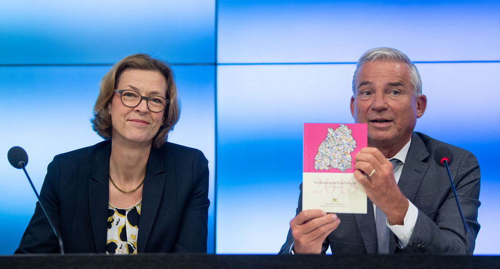 Innenminister Thomas Strobl (r.) zeigt während einer Pressekonferenz den Verfassungsschutzbericht 2018 Baden-Württemberg, daneben sitzt Beate Bube (l.), Präsidentin des Landesamtes für Verfassungsschutz (Bild: © picture alliance/Marijan Murat/dpa)