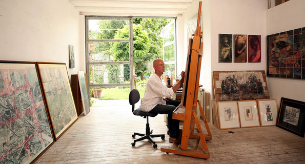 Ein Künstler an der Staffelei arbeitet im Atelier. 
