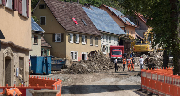 Bagger stehen in Braunsbach auf der Straße. Eine Woche nach dem Unwetter laufen die Aufräumarbeiten in dem schwer getroffenen Ort (Bild: © dpa).