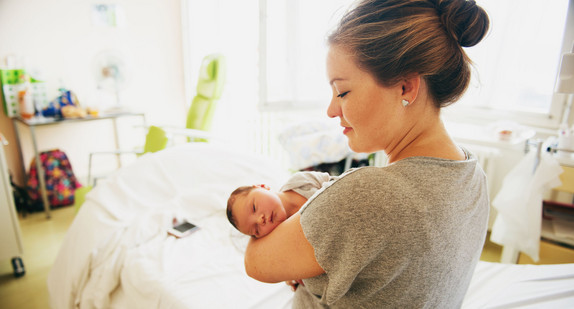 Glückliche junge Mutter mit neugeborenem Baby im Krankenhaus nach der Geburt.