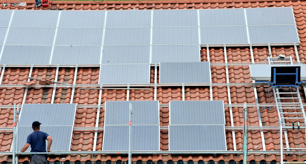 Ein Arbeiter installiert in St. Peter im Hochschwarzwald auf dem Dach eines Kleinunternehmens eine Solaranlage. (Bild: dpa)