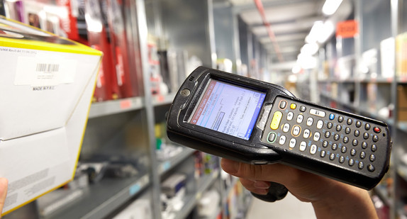 Ein Mitarbeiter scannt den Barcode eines Artikels für den Paketversand. (Bild: © dpa)
