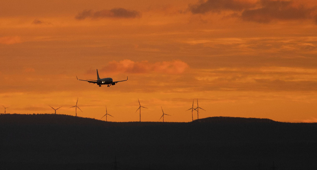 Ein Flugzeug landet am Flughafen Stuttgart, im Hintergrund stehen Windräder. (Bild: picture alliance/Marijan Murat/dpa)
