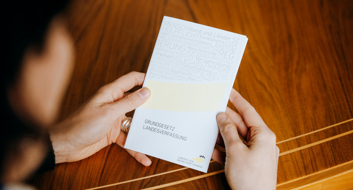Eine Person hält die Landesverassung in den Händen.