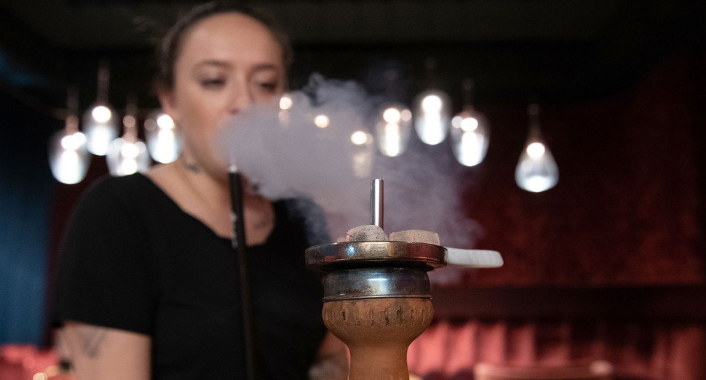Eine Frau raucht eine Shisha in einer Shisha-Bar (Bild: © dpa).
