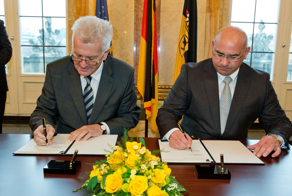 Ministerpräsident Winfried Kretschmann (l.) und Daniel Strauß (r.) unterzeichnen den Staatsvertrag