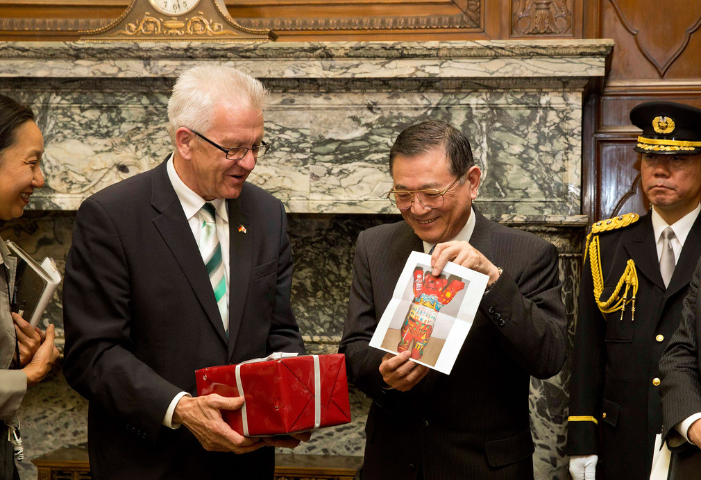 Der Präsident des japanischen Oberhauses, Kenji Hirata (r.), und Bundesratspräsident und Ministerpräsident Winfried Kretschmann (l.) tauschen Geschenke aus.