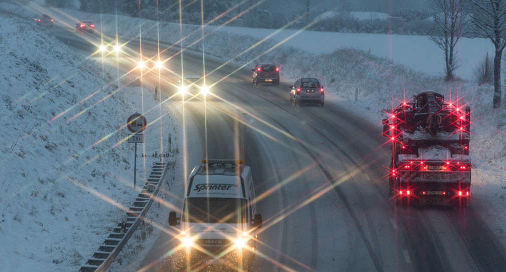 Autos fahren auf der schneebedeckten Fahrbahn. (Bild: © dpa)