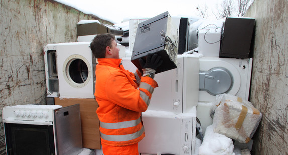 Eine Fachkraft für Abfallwirtschaft auf dem Wertstoffhof in Stuttgart-Münster stapelt größere Elektrogeräte. (Bild: dpa)