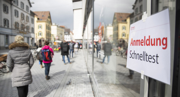 Einige Menschen stehen in einer Schlange, um sich für einen Schnelltest in der Tübinger Innenstadt anzumelden.