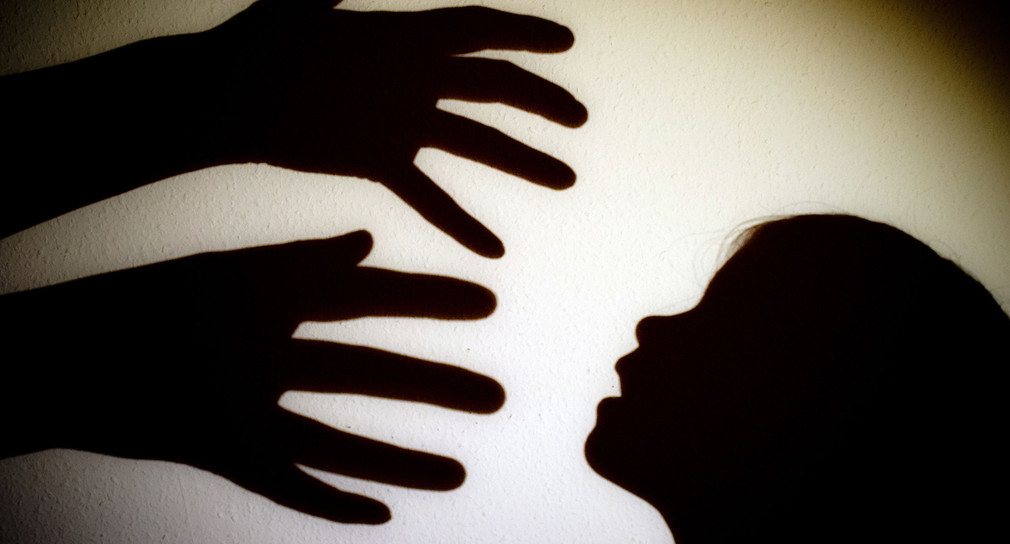 Schatten von den Händen einer erwachsenen Person und dem Kopf eines Kindes (Bild: © dpa)