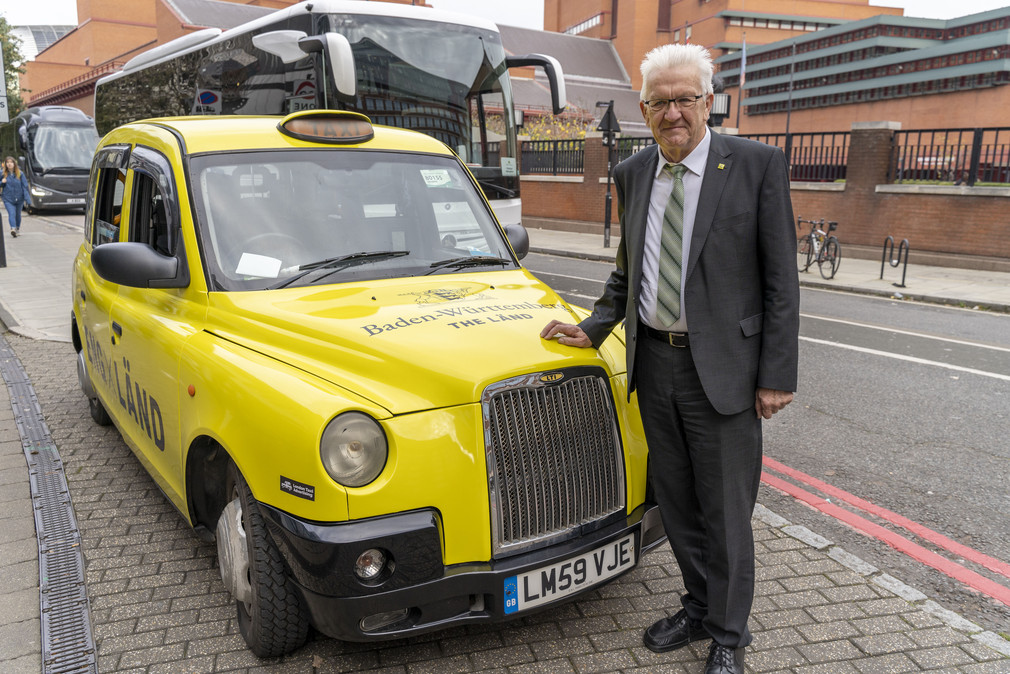 Ministerpräsident Winfried Kretschmann vor einem Londoner Taxi im Design der neuen „THE LÄND“-Kampagne