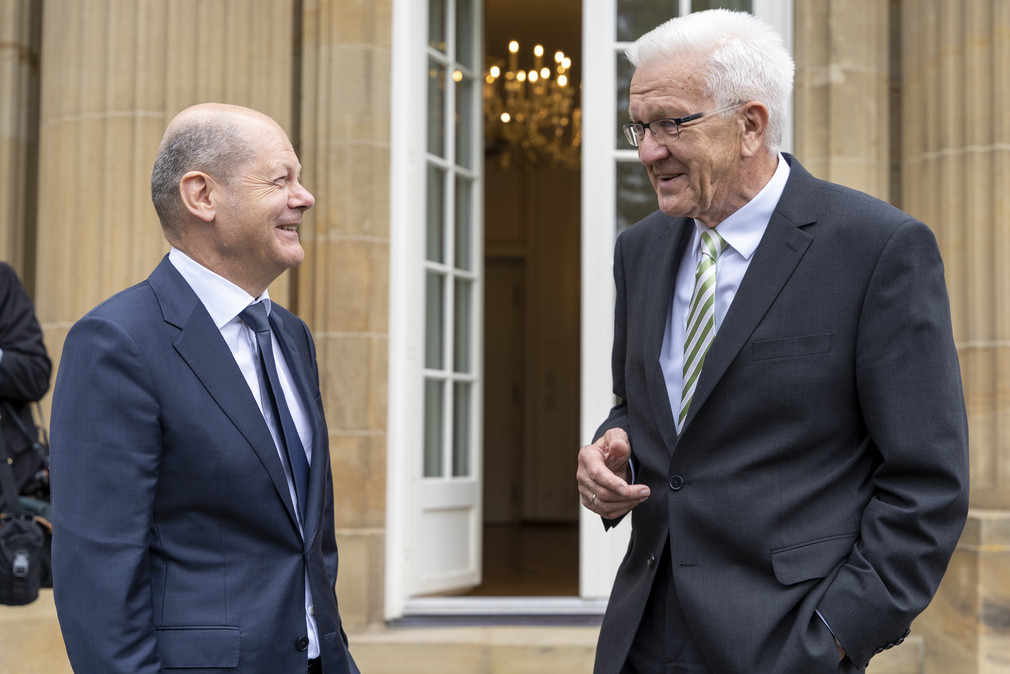 Ministerpräsident Winfried Kretschmann (r.) und Bundeskanzler Olaf Scholz (l.) stehen auf der Terrasse der Villa Reitzenstein, dem Amtssitz des Ministerpräsidenten von Baden-Württemberg in Stuttgart. Beide sind miteinander im Gespräch. 
