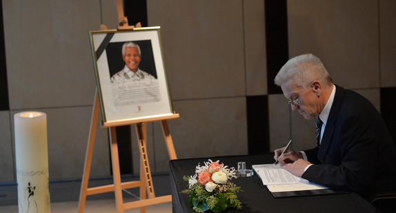 Ministerpräsident Winfried Kretschmann trägt sich in das Kondolenzbuch für Nelson Mandela ein.