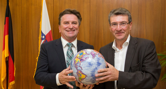 Thüringens Integrationsminister Dieter Lauinger (r.) überreicht Sozial- und Integrationsminister Manne Lucha (l.) zum Vorsitz der Integrationsministerkonferenz symbolisch eine Weltkugel. (Foto: dpa)