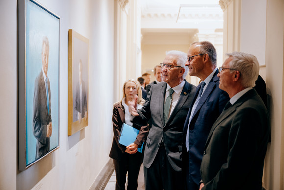 von links nach rechts: Ministerpräsident Winfried Kretschmann, Bundeskanzler Friedrich Merz und Innenminister Thomas Strobl betrachten die Porträts der früheren Ministerpräsidenten von Baden-Württemberg
