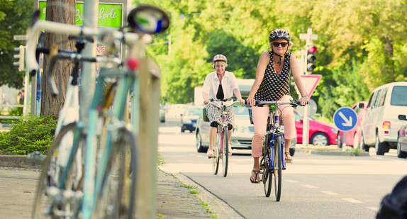 Zwei Radfahrerinnen fahren auf dem Fahrradstreifen einer Straße.