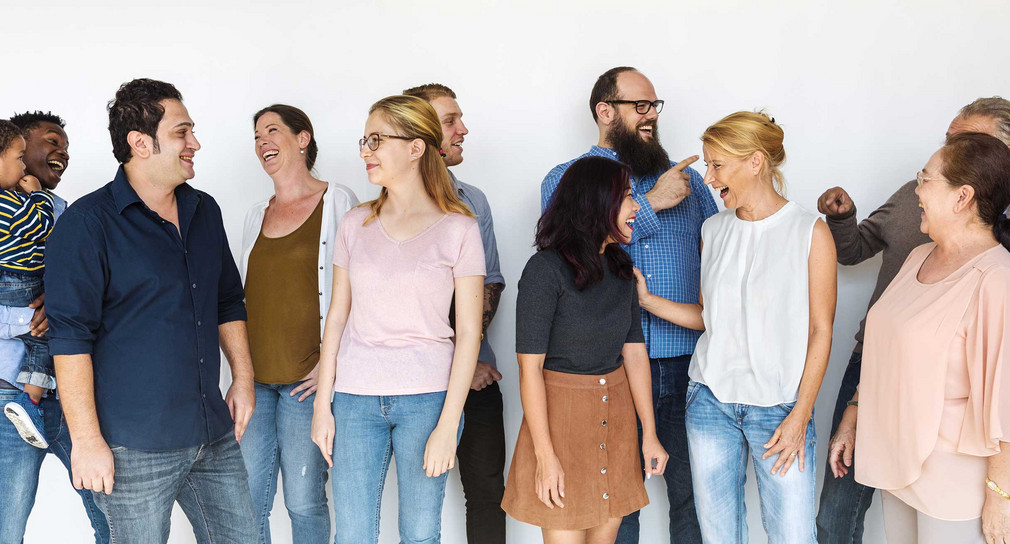 Eine bunt gemischte Gruppe Menschen steht vor einer Wand.