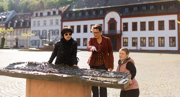 Sozialbürgermeisterin Stefanie Jansen, Christina Reiß und Simone Fischer vor dem Blindentastmodell am Karlsplatz in Heidelberg.