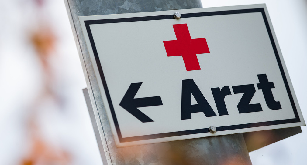 Ein Schild mit der Aufschrift „Arzt“ hängt an einer Straßenlaterne.