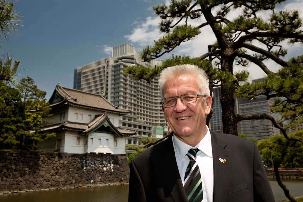 Ministerpräsident Winfried Kretschmann vor einem Teil des Kaiserpalastes und Hochhäusern in Tokio (Japan)